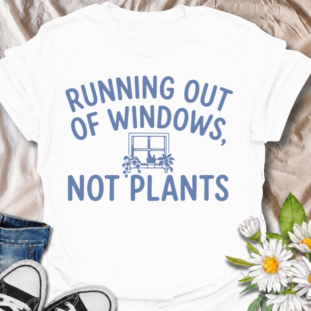 A funny houseplant T-shirt for anyone who is running out of sunny windows long before they are running out of plants. The phrase “Running Out of Windows, Not Plants” captures the reality of an ever-growing indoor jungle with simple, relatable humor. Featuring a small windowsill filled with potted plants, the design is perfect for plant parents, houseplant collectors, and indoor gardeners. It makes a great gift for anyone whose best light has already been claimed by greenery. Perfect for nursery trips, plant