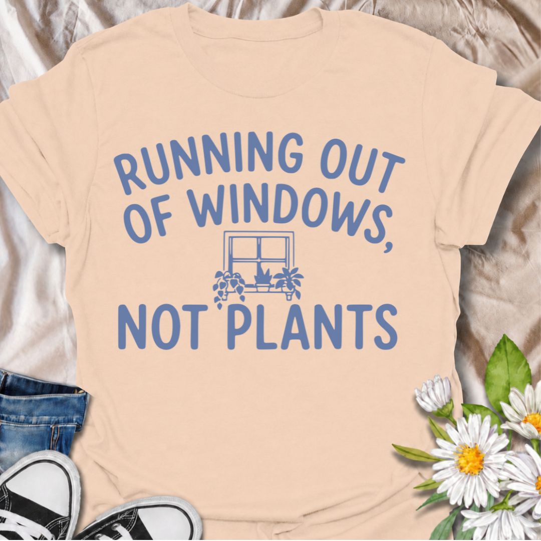 A funny houseplant T-shirt for anyone who is running out of sunny windows long before they are running out of plants. The phrase “Running Out of Windows, Not Plants” captures the reality of an ever-growing indoor jungle with simple, relatable humor. Featuring a small windowsill filled with potted plants, the design is perfect for plant parents, houseplant collectors, and indoor gardeners. It makes a great gift for anyone whose best light has already been claimed by greenery. Perfect for nursery trips, plant
