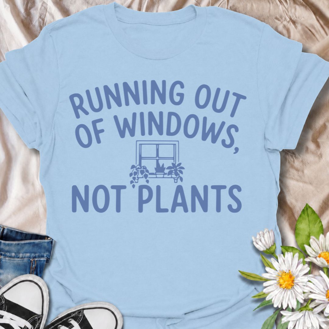 A funny houseplant T-shirt for anyone who is running out of sunny windows long before they are running out of plants. The phrase “Running Out of Windows, Not Plants” captures the reality of an ever-growing indoor jungle with simple, relatable humor. Featuring a small windowsill filled with potted plants, the design is perfect for plant parents, houseplant collectors, and indoor gardeners. It makes a great gift for anyone whose best light has already been claimed by greenery. Perfect for nursery trips, plant