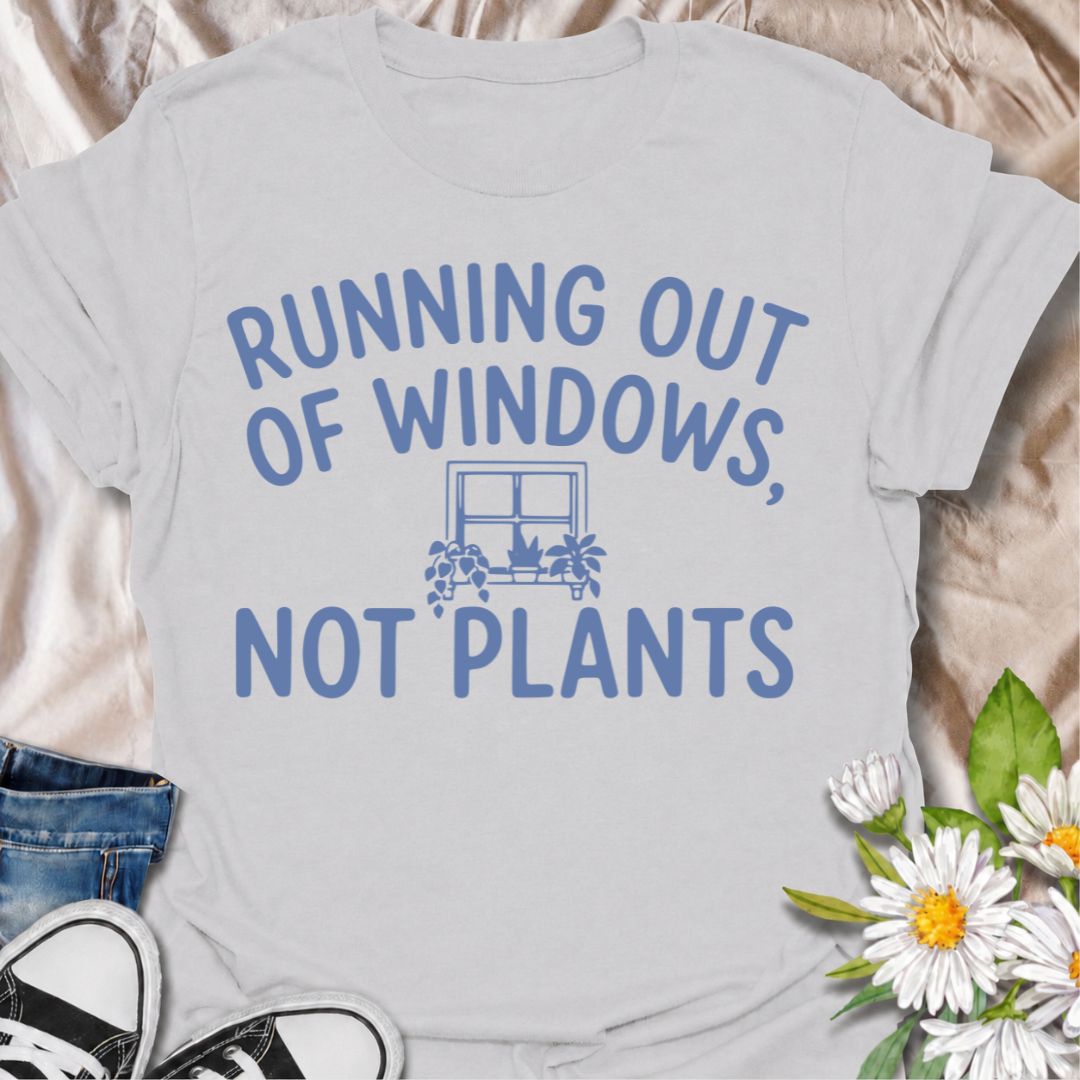 A funny houseplant T-shirt for anyone who is running out of sunny windows long before they are running out of plants. The phrase “Running Out of Windows, Not Plants” captures the reality of an ever-growing indoor jungle with simple, relatable humor. Featuring a small windowsill filled with potted plants, the design is perfect for plant parents, houseplant collectors, and indoor gardeners. It makes a great gift for anyone whose best light has already been claimed by greenery. Perfect for nursery trips, plant