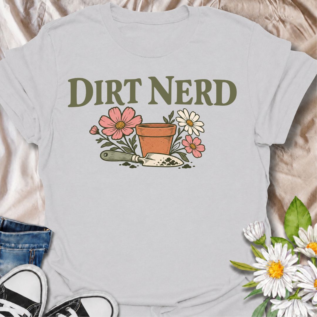 A playful gardening T-shirt for anyone who genuinely gets excited about soil, pots, planting, and everything that goes with growing things. The simple “Dirt Nerd” phrase pairs with flowers, a terracotta pot, and hand trowel for a clean garden-lover design with plenty of personality. It is perfect for backyard gardeners, flower growers, cottage gardeners, and anyone who is happiest with their hands in the soil. The soft vintage-style artwork keeps the design cheerful and easy to wear. A great gift for garden