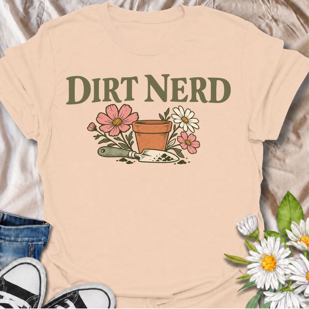 A playful gardening T-shirt for anyone who genuinely gets excited about soil, pots, planting, and everything that goes with growing things. The simple “Dirt Nerd” phrase pairs with flowers, a terracotta pot, and hand trowel for a clean garden-lover design with plenty of personality. It is perfect for backyard gardeners, flower growers, cottage gardeners, and anyone who is happiest with their hands in the soil. The soft vintage-style artwork keeps the design cheerful and easy to wear. A great gift for garden