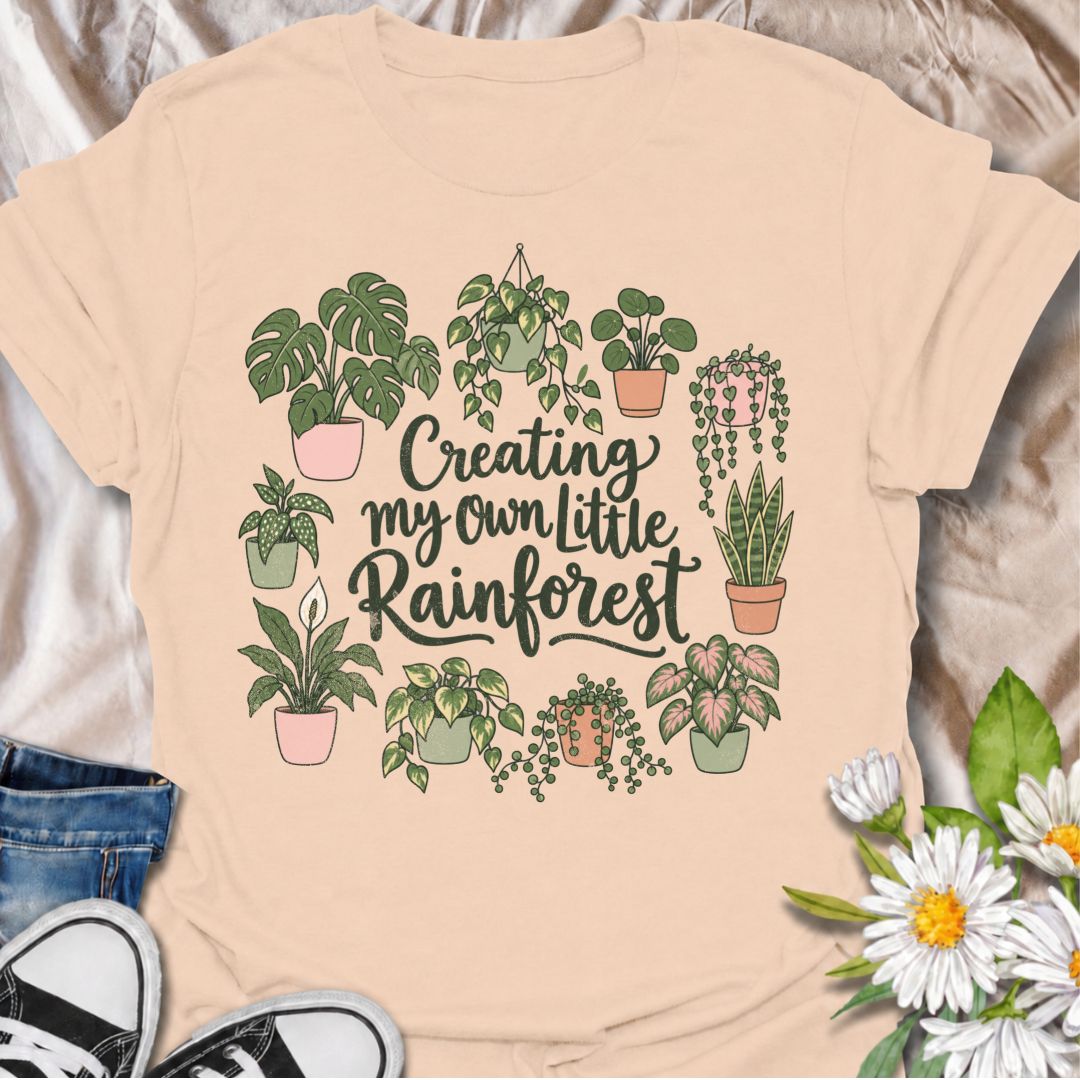A charming houseplant T-shirt for anyone who is slowly turning their home into a lush indoor jungle. The phrase “Creating My Own Little Rainforest” is surrounded by monstera, pothos, snake plants, trailing vines, and other leafy favorites for a soft botanical design. It is perfect for plant parents, houseplant collectors, indoor gardeners, and anyone who loves filling every spare corner with greenery. The hand-drawn styling gives it a warm, feminine feel while keeping the design easy to wear. A lovely gift 