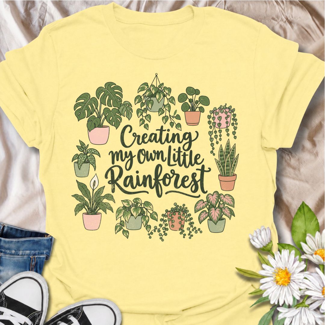 A charming houseplant T-shirt for anyone who is slowly turning their home into a lush indoor jungle. The phrase “Creating My Own Little Rainforest” is surrounded by monstera, pothos, snake plants, trailing vines, and other leafy favorites for a soft botanical design. It is perfect for plant parents, houseplant collectors, indoor gardeners, and anyone who loves filling every spare corner with greenery. The hand-drawn styling gives it a warm, feminine feel while keeping the design easy to wear. A lovely gift 