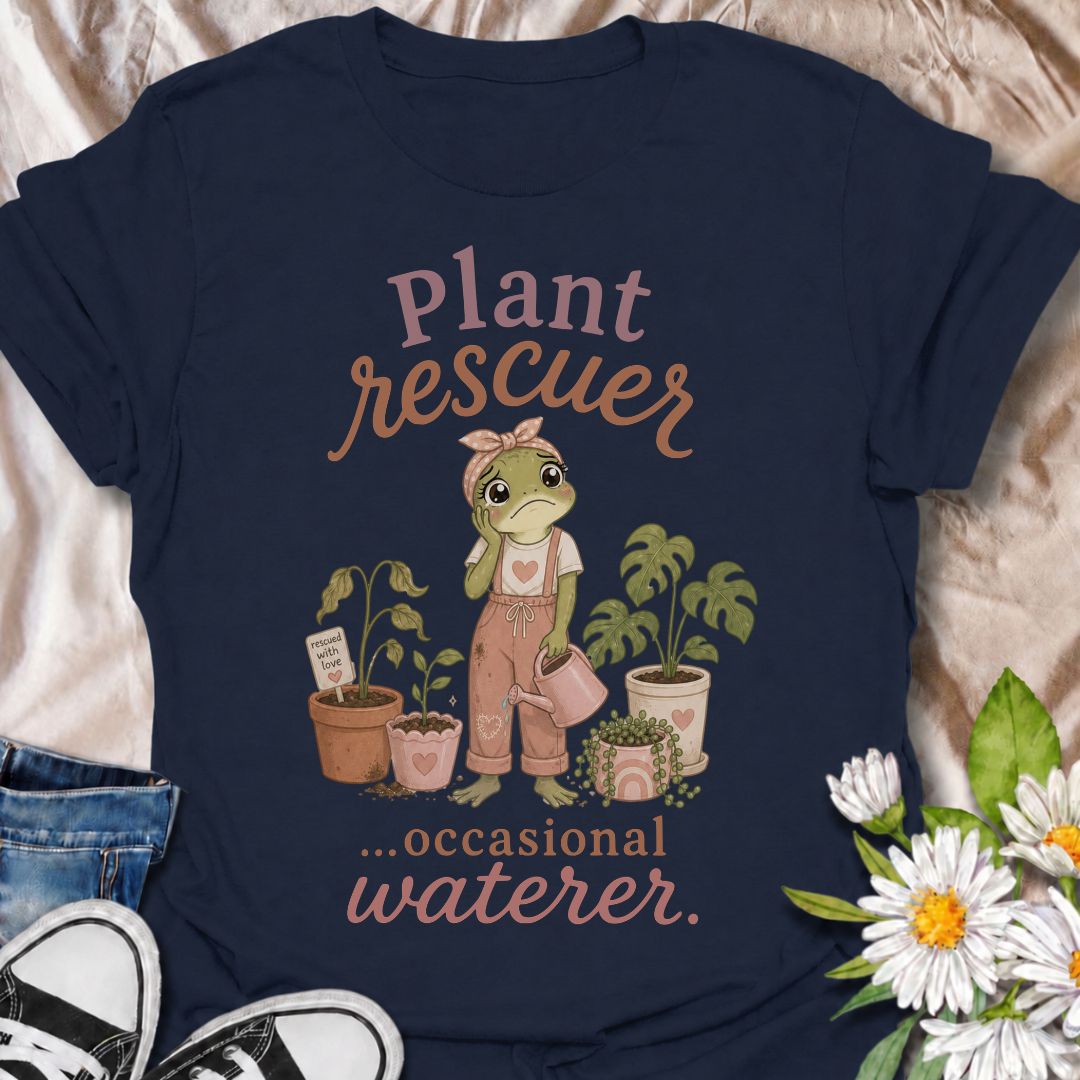 A funny plant T-shirt for anyone who cannot resist trying to save a struggling houseplant. The phrase “Plant Rescuer… Occasional Waterer” pairs with a sweet frog character, wilted plants, watering can, and potted greenery for playful, self-aware plant-parent humor. It is perfect for houseplant lovers, indoor gardeners, and anyone who brings home sad plants with every intention of nursing them back to health. The softer pastel artwork gives the design a warm, feminine feel while keeping the joke clear and re