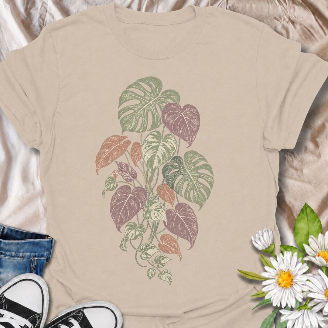 A soft botanical T-shirt for plant lovers who prefer their greenery with a more subtle, feminine feel. Featuring layered monstera, philodendron, and trailing leaves in muted sage, dusty rose, and soft plum tones, this design has an understated vintage look that works beautifully for everyday wear. It is perfect for houseplant lovers, indoor gardeners, botanical enthusiasts, and anyone who enjoys nature-inspired clothing without a slogan. The faded palette gives the artwork a relaxed, slightly worn-in feel w