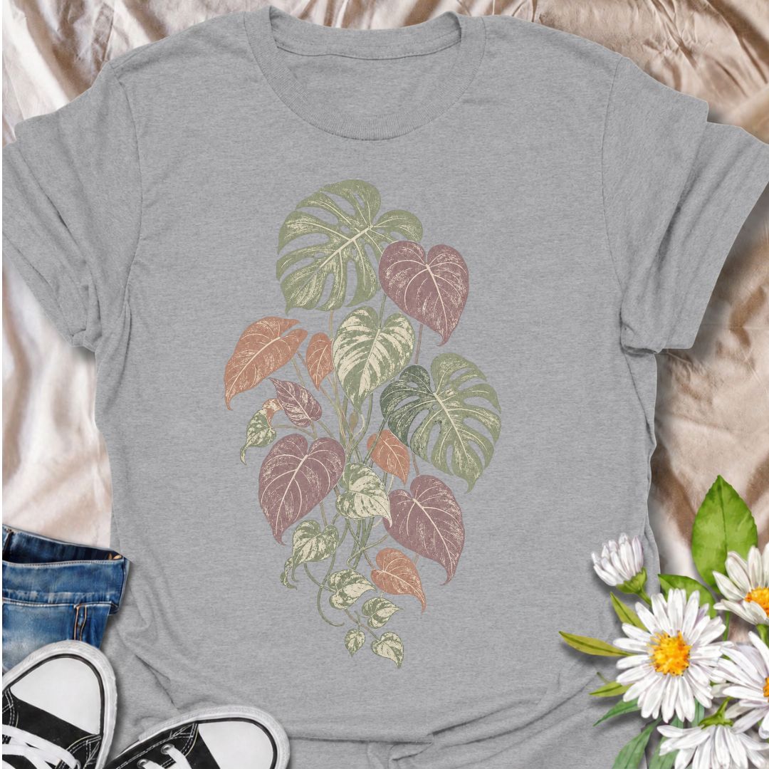 A soft botanical T-shirt for plant lovers who prefer their greenery with a more subtle, feminine feel. Featuring layered monstera, philodendron, and trailing leaves in muted sage, dusty rose, and soft plum tones, this design has an understated vintage look that works beautifully for everyday wear. It is perfect for houseplant lovers, indoor gardeners, botanical enthusiasts, and anyone who enjoys nature-inspired clothing without a slogan. The faded palette gives the artwork a relaxed, slightly worn-in feel w