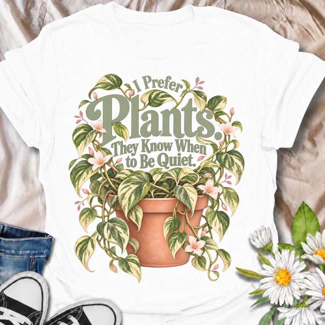A charming plant T-shirt for anyone who prefers the company of houseplants and appreciates a little peace and quiet. The phrase “I Prefer Plants. They Know When to Be Quiet.” pairs with a lush variegated trailing plant, soft pink flowers, and a terracotta pot for gentle, relatable plant-lover humor. It is perfect for plant parents, houseplant collectors, indoor gardeners, and anyone who enjoys calm spaces filled with greenery. The muted sage, cream, blush, and terracotta palette gives the design a softer, m