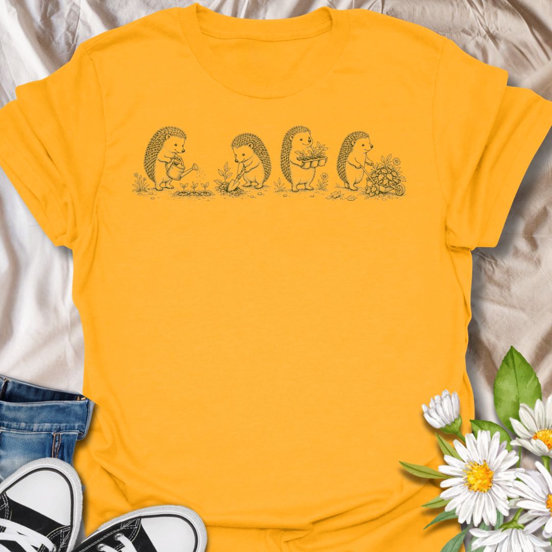 This Gardening Hedgehogs t-shirt is made for gardeners, nature lovers, and woodland animal fans who enjoy sweet vintage-style artwork. Featuring four charming hedgehogs watering, digging, carrying plants, and pushing a flower-filled wheelbarrow, this design has a gentle cottagecore garden feel. Perfect for plant lovers, gardeners, hedgehog fans, wildlife lovers, botanical art fans, and anyone who loves soft nature-inspired designs.