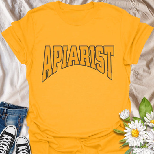 Simple bold "Apiarist" t-shirt with collegiate-style yellow lettering on black. Perfect for professional beekeepers, hobbyist beekeepers, honey producers, and bee conservation advocates. Great gift for anyone passionate about apiculture, bee science, or protecting pollinators.