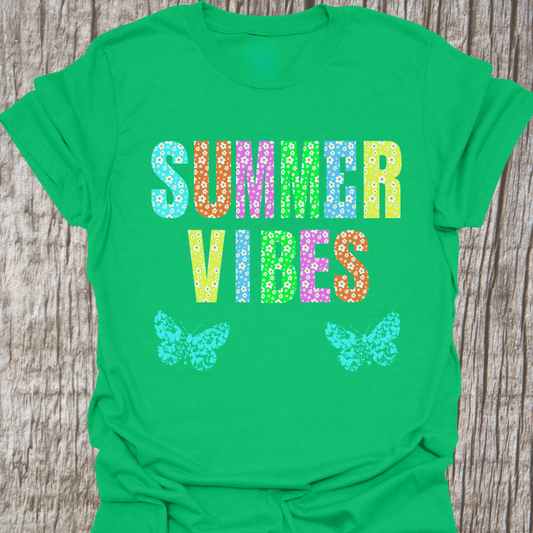 Bright, cheerful T-shirt with large text filled with flower pattern.  Text reads "Summer Vibes" There are two butterflies at the bottom of the design.  T-shirt is Irish Green