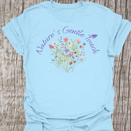 Beautiful flowers light blue T-shirt, 'Nature's Gentle Touch' curving around flowers in a lilac font, and a butterfly gently resting within the design.
