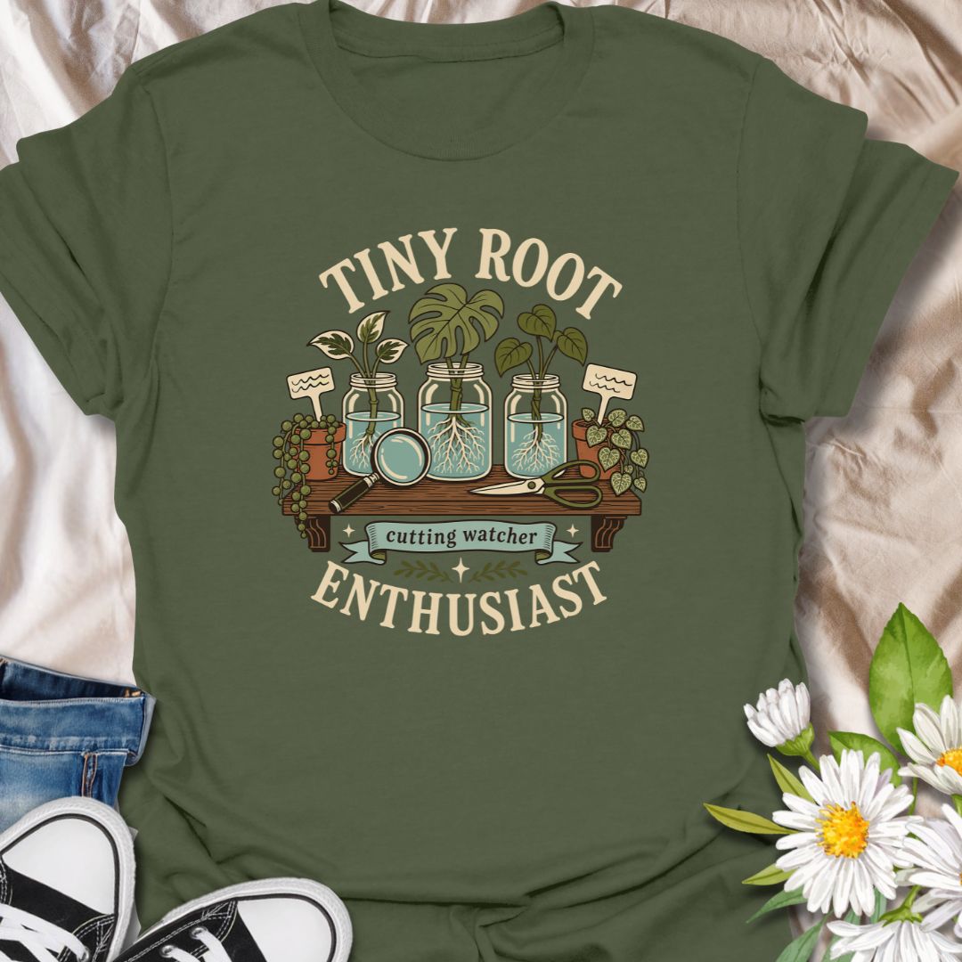 A playful propagation T-shirt for anyone fascinated by the first tiny roots appearing on a cutting. The design features glass jars, water-propagated plants, a magnifying glass, pruning shears, and trailing greenery. A thoughtful gift for houseplant lovers, propagation fans, and patient indoor gardeners.
