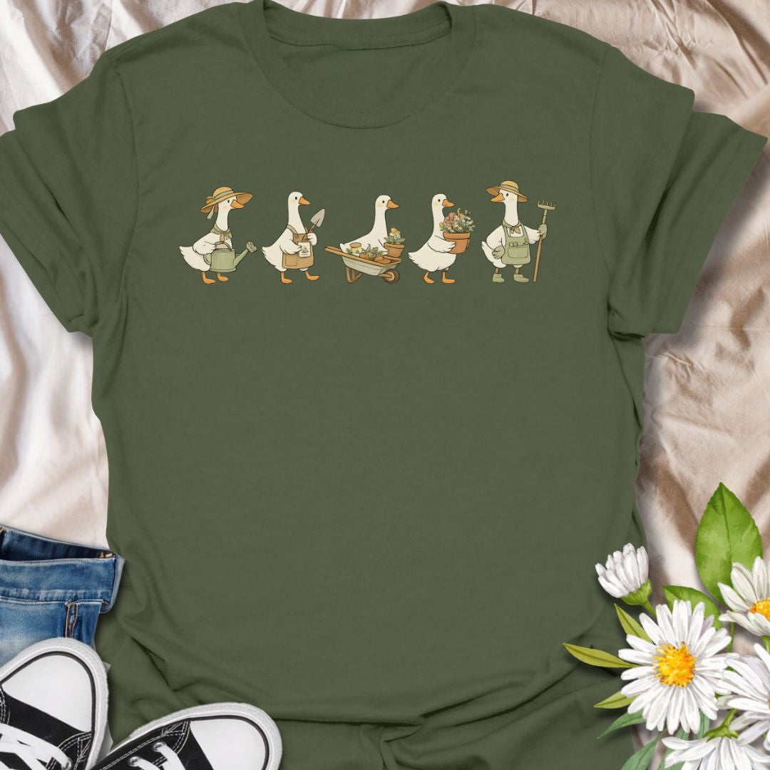 This Gardening Geese t-shirt is made for gardeners, plant lovers, and anyone who enjoys cute nature-inspired artwork with a little humor. Featuring a row of charming geese carrying watering cans, garden tools, flower pots, a wheelbarrow, and fresh plants, this design has a playful cottagecore garden feel that is easy to wear. Perfect for gardeners, duck lovers, plant moms, flower fans, backyard growers, and anyone who thinks garden chores are better with a gaggle of helpful Geese.