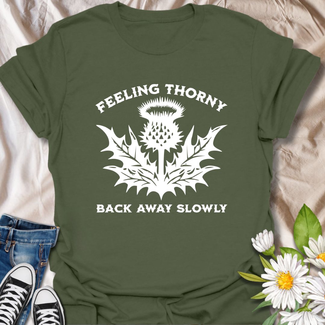 Embrace your mood with this witty “Feeling Thorny – Back Away Slowly” t-shirt featuring a bold thistle graphic. Perfect for introverts, plant lovers, and anyone with a sharp sense of humor, this quirky design makes a great gift or statement piece for everyday wear.