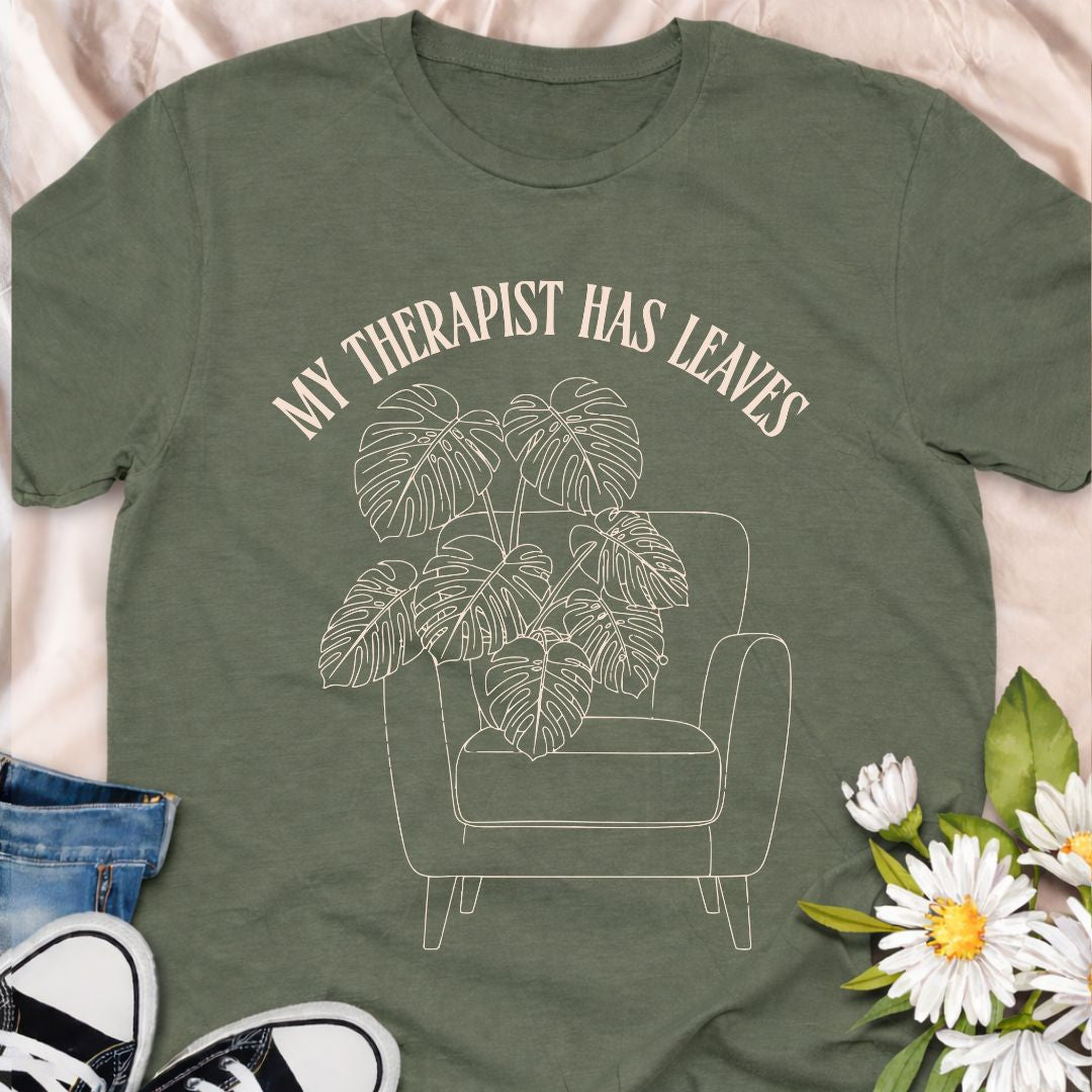 For plant people who spill their heart out to their houseplants, this “My Therapist Has Leaves” t-shirt says it all. Features a cozy armchair and lush monstera, making it the perfect aesthetic plant lover tee for self-care days.
