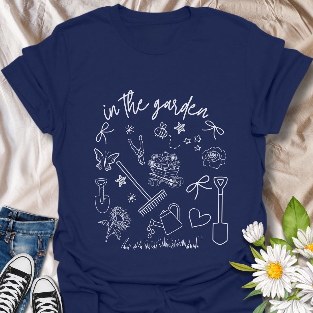 Charming "In The Garden" doodle style t-shirt with hand-drawn gardening tools, flowers, and butterflies. Perfect gift for gardeners, plant lovers, and nature enthusiasts. Stylish botanical apparel for spring, summer, or everyday wear. Celebrate your green thumb!