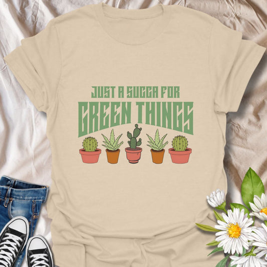 Embrace your love for all things leafy with this playful “Just a Succa for Green Things” t-shirt. Featuring a lineup of adorable potted succulents and bold retro typography, it’s perfect for plant lovers with a sense of humor.