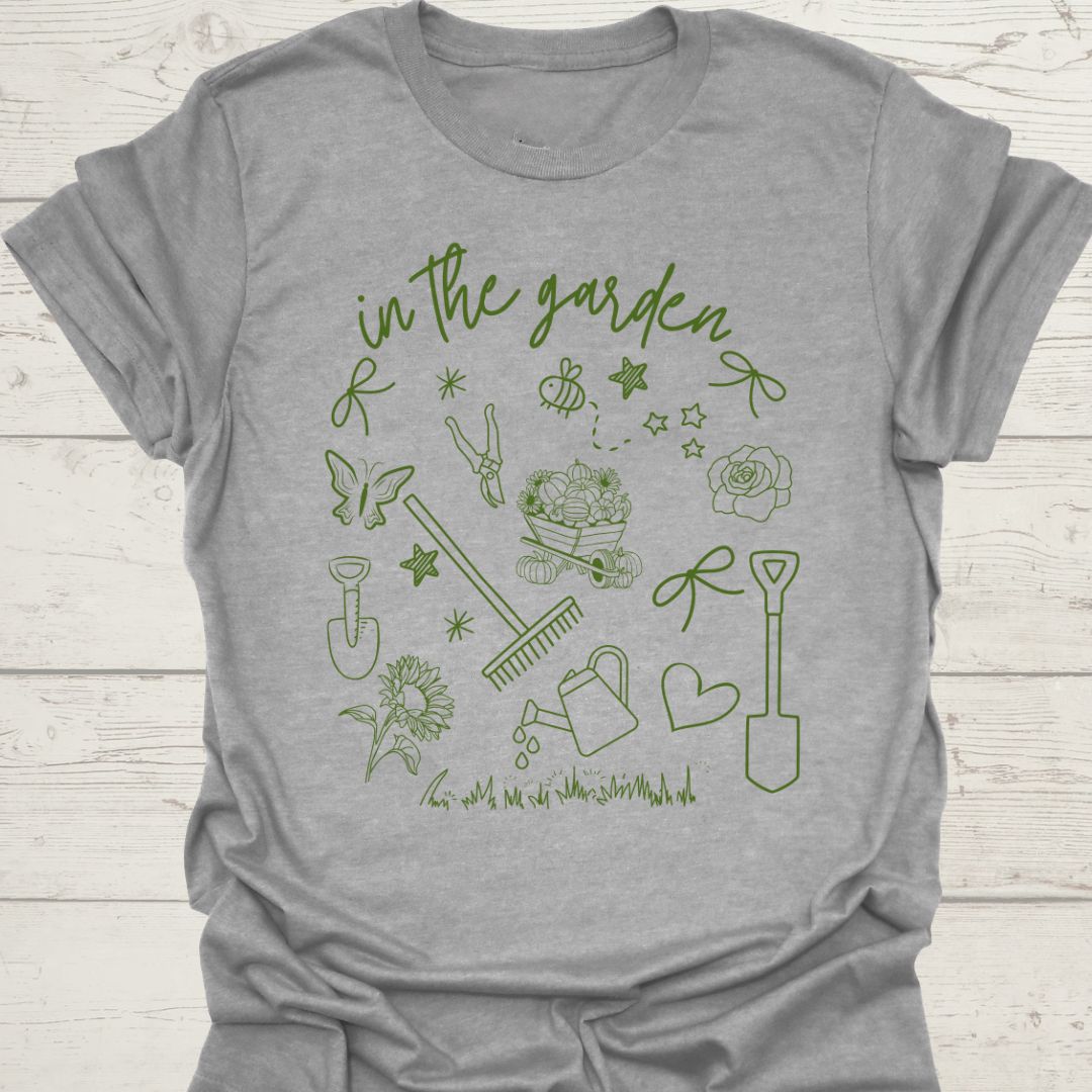 Garden Doodle on a T-shirt!  This doodle has garden tools, flowers, grass, bees, butterfly and lots more, green images and text saying 'in the garden'  on a sport grey t-shirt