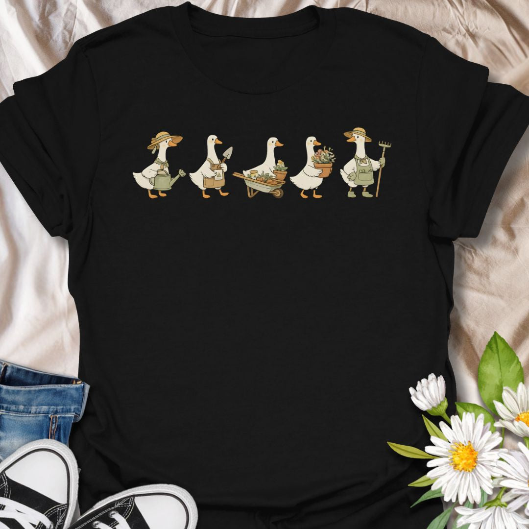 This Gardening Geese t-shirt is made for gardeners, plant lovers, and anyone who enjoys cute nature-inspired artwork with a little humor. Featuring a row of charming geese carrying watering cans, garden tools, flower pots, a wheelbarrow, and fresh plants, this design has a playful cottagecore garden feel that is easy to wear. Perfect for gardeners, duck lovers, plant moms, flower fans, backyard growers, and anyone who thinks garden chores are better with a gaggle of helpful Geese.