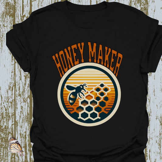 Black T-shirt featuring a circular design with a bee and honeycomb, accompanied by the text "Honey Maker" in orange.
