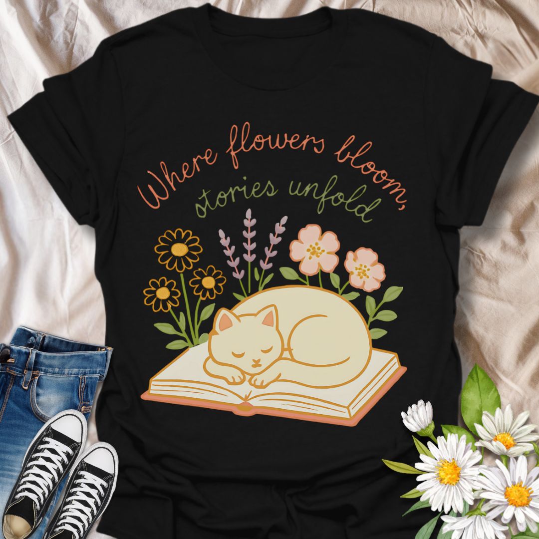 Cozy cat and book t-shirt with pastel flowers and the quote 'Where flowers bloom, stories unfold.' Perfect for book lovers, cat moms, gardeners, and daydreamers who adore cottagecore and literary aesthetics. Soft and sweet tee ideal for spring, reading nooks, and gifting.
