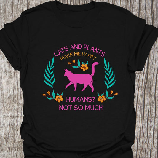Cat and Plants Make Me Happy, Humans? Not So Much text and image design with pink cat as main image and decorative leaves, and flowers.  Black t-shirt