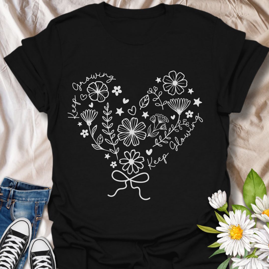 Charming floral heart t-shirt featuring delicate hand-drawn flowers with positive affirmations “Keep Growing, Keep Glowing.” A perfect uplifting gift for gardeners and plant lovers.  Black