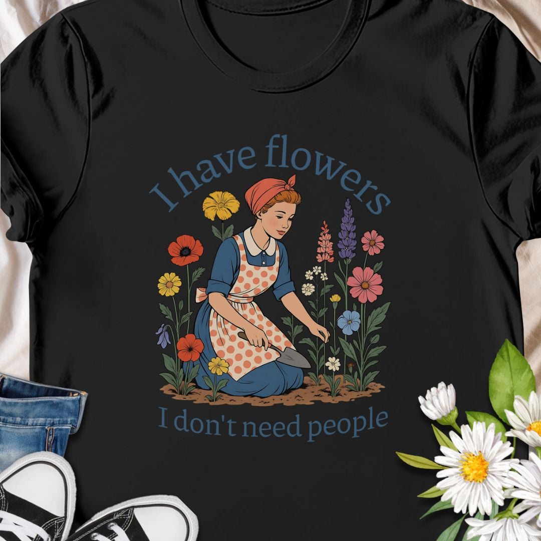 Express your introverted, plant-loving side with this charming floral t-shirt. Perfect for gardeners, plant moms, or anyone who finds peace in flowers over people — it's a blooming statement of self-care.  This tee pairs vintage garden charm with a wry sense of independence. A retro-style gardener tends bright, cottage blooms while the caption reads “I have flowers / I don’t need people.” 