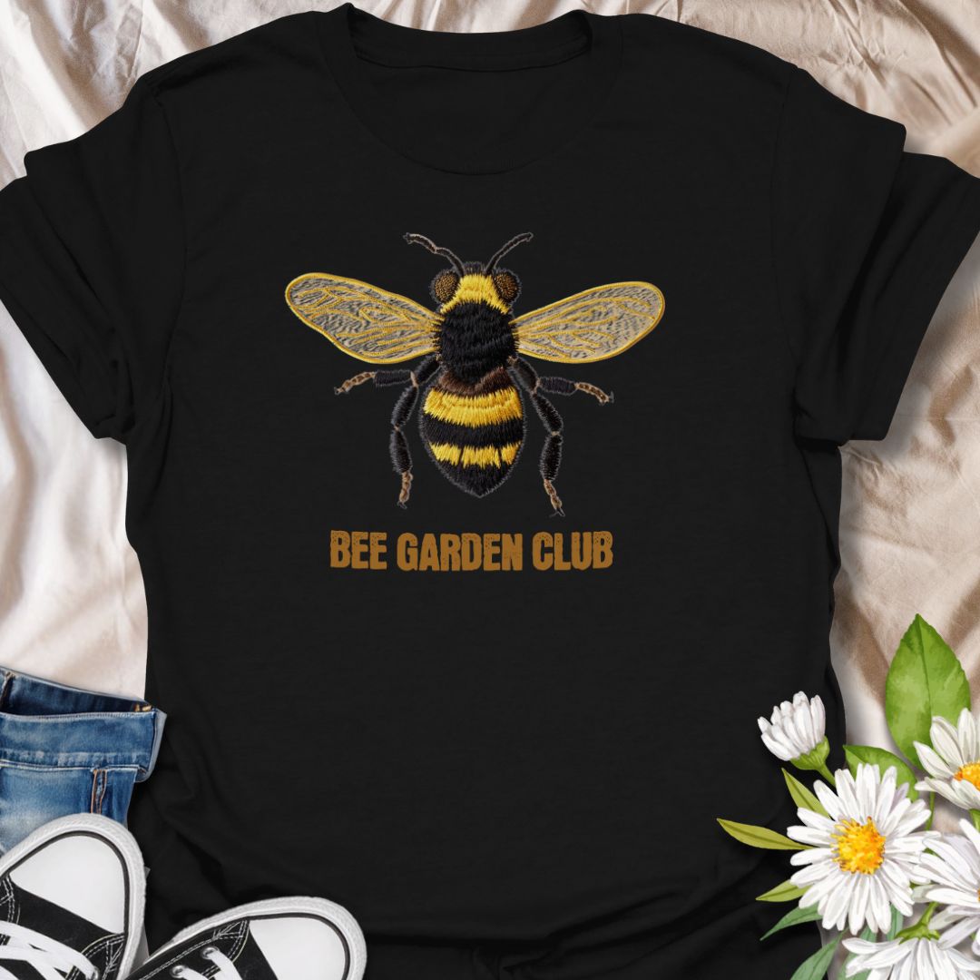 This Bee Garden Club t-shirt is made for gardeners, pollinator lovers, and nature fans who want a simple bee design with a refined botanical feel. Featuring a detailed faux-embroidered bee with golden wings, fuzzy black and yellow stripes, and clean Bee Garden Club lettering, this design has a classic garden-club look that is easy to wear. Perfect for bee lovers, gardeners, wildflower fans, pollinator supporters, nature lovers, and anyone who wants to celebrate the garden’s hardest little workers.