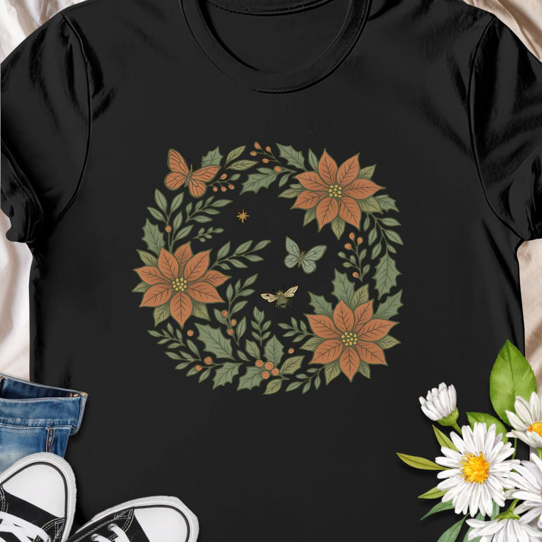 Festive botanical tee featuring a Christmas wreath with poinsettias, bees, and butterflies. Perfect holiday wear for plant lovers.