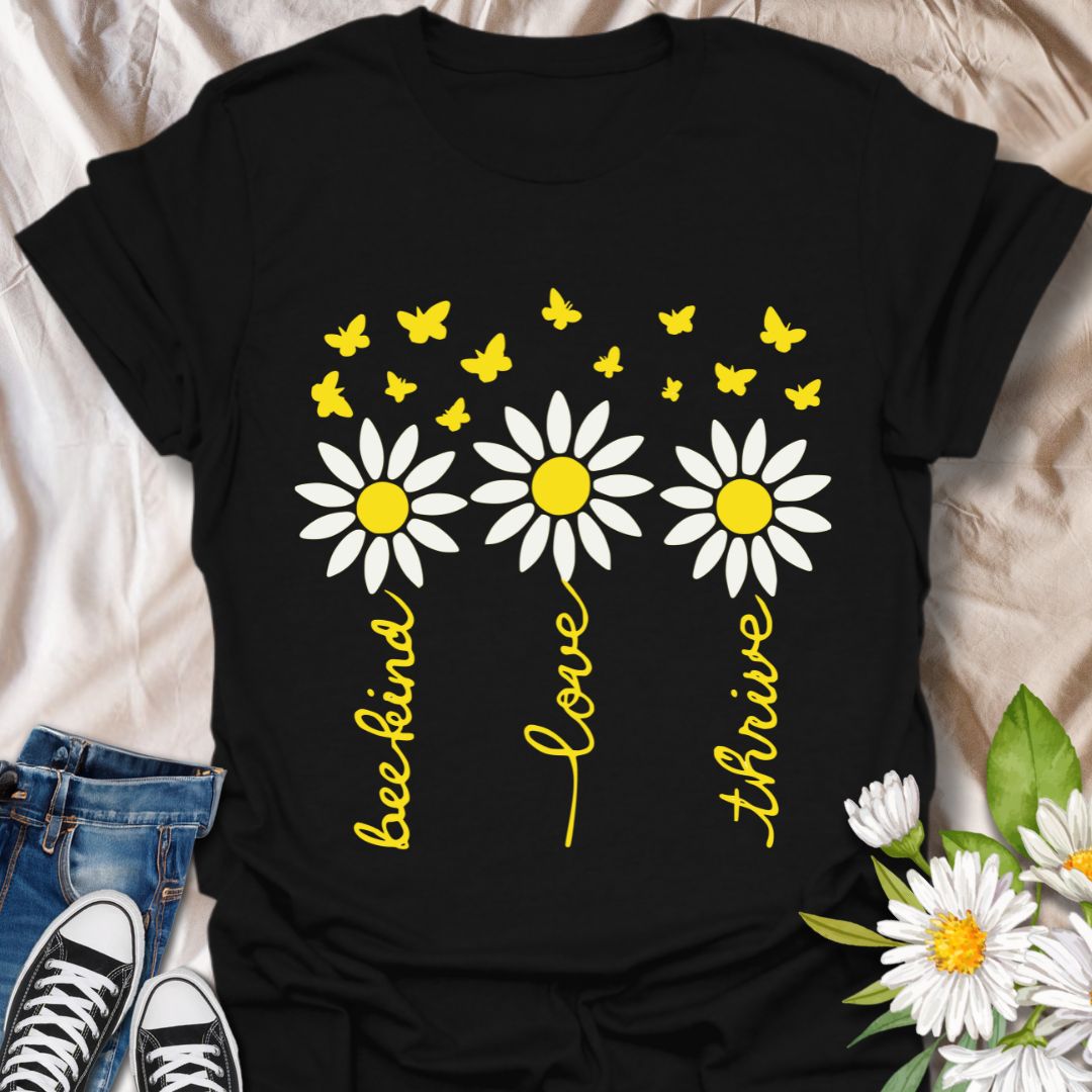 Inspire positivity with this uplifting floral graphic t-shirt featuring hand-lettered words be kind, love, thrive paired with charming daisies and fluttering butterflies. A perfect gift for flower lovers, kind souls, and anyone