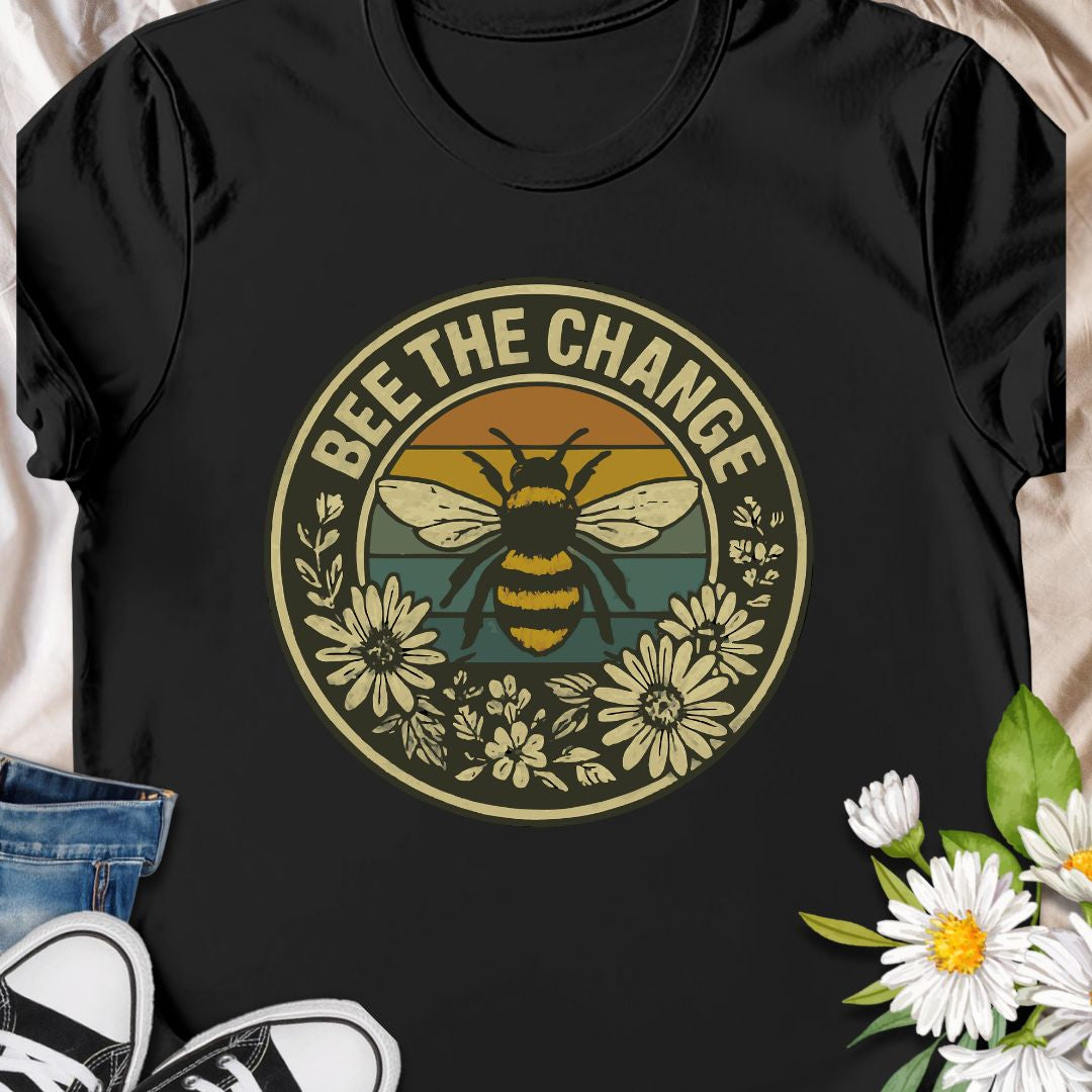 Spread positivity and environmental awareness with this vintage-style “Bee The Change” t-shirt. Featuring a bold bee illustration surrounded by wildflowers and retro sunset colors, it’s perfect for nature lovers, pollinator protectors, and eco-conscious souls. Makes a thoughtful gift for beekeepers, gardeners, or anyone who believes in making a difference—one bee at a time.