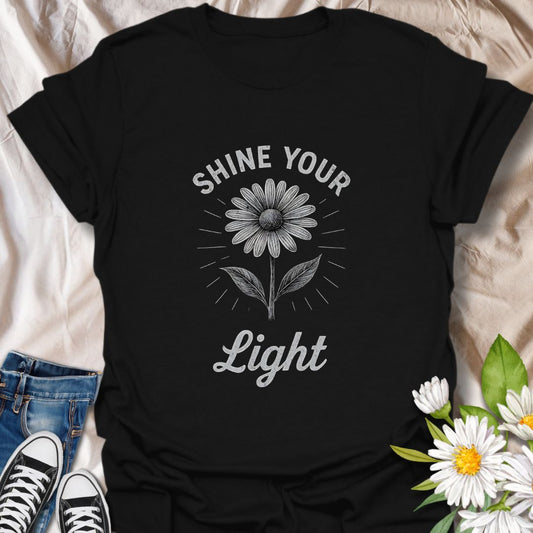 Spread positivity with this uplifting graphic t-shirt featuring a blooming daisy and the inspirational phrase "Shine Your Light." Perfect for flower lovers, mindful living enthusiasts, and anyone who enjoys wearing motivational, nature-inspired apparel.