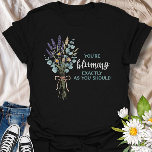 Celebrate growth and self-love with this elegant floral quote t-shirt. Featuring a beautifully illustrated bouquet and the inspiring words "You're blooming exactly as you should", this black tee is perfect for anyone on a journey of personal growth. A thoughtful gift for plant lovers, teachers, mental health advocates, or anyone who appreciates uplifting messages in nature-inspired fashion.