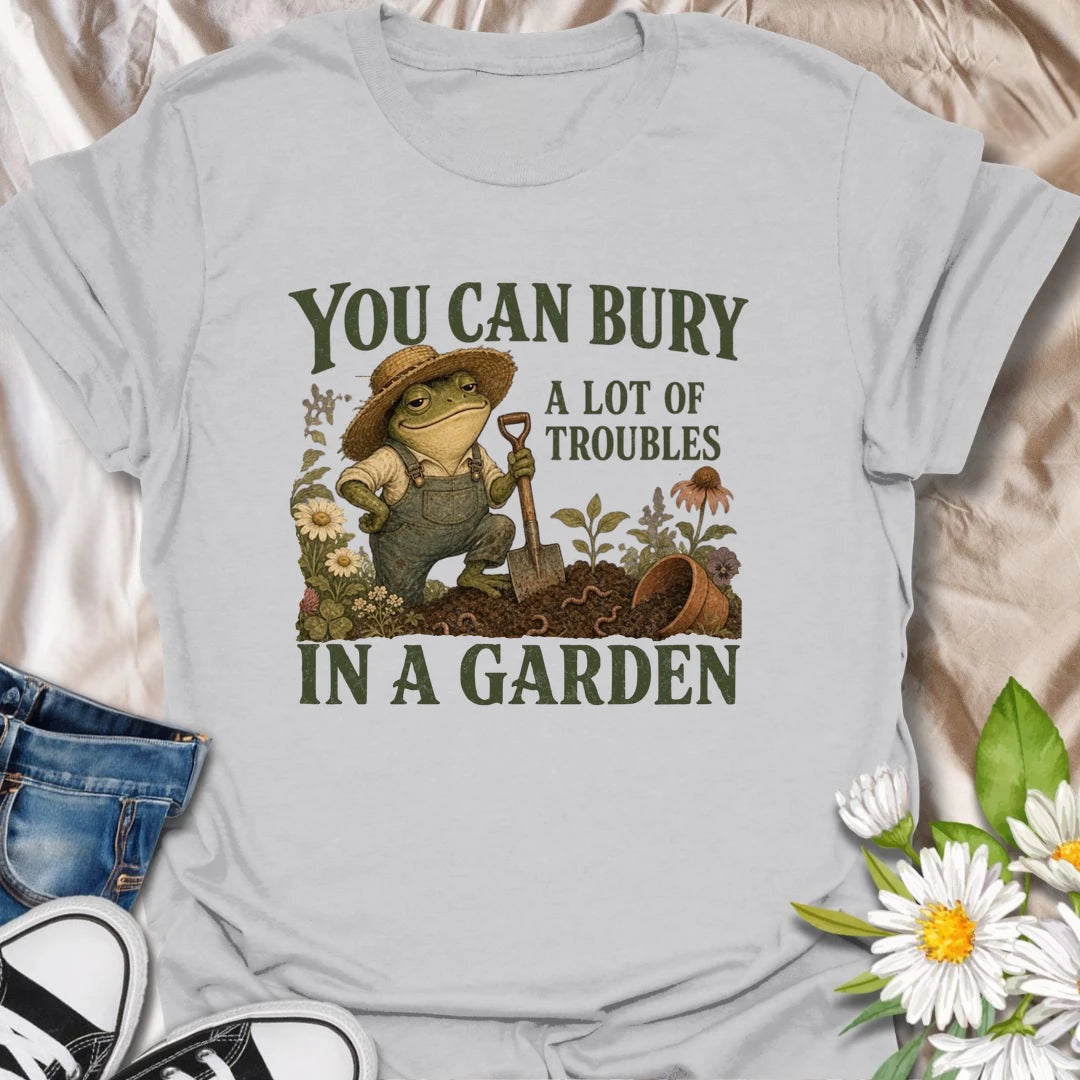 Funny gardening t-shirt with a charming frog and the classic saying about burying troubles in a garden.
Features vintage-style garden art with flowers, rich soil, and a playful frog gardener holding a shovel.
A great gift for gardeners, frog lovers, flower lovers, and anyone who finds peace and humor in the garden.