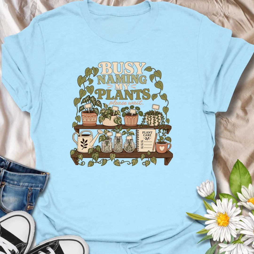 A funny plant lover T-shirt for anyone who treats every houseplant like part of the family. The detailed design features potted plants, propagation jars, gardening tools, and a plant care notebook. A charming gift for plant moms, houseplant collectors, and indoor gardening enthusiasts.