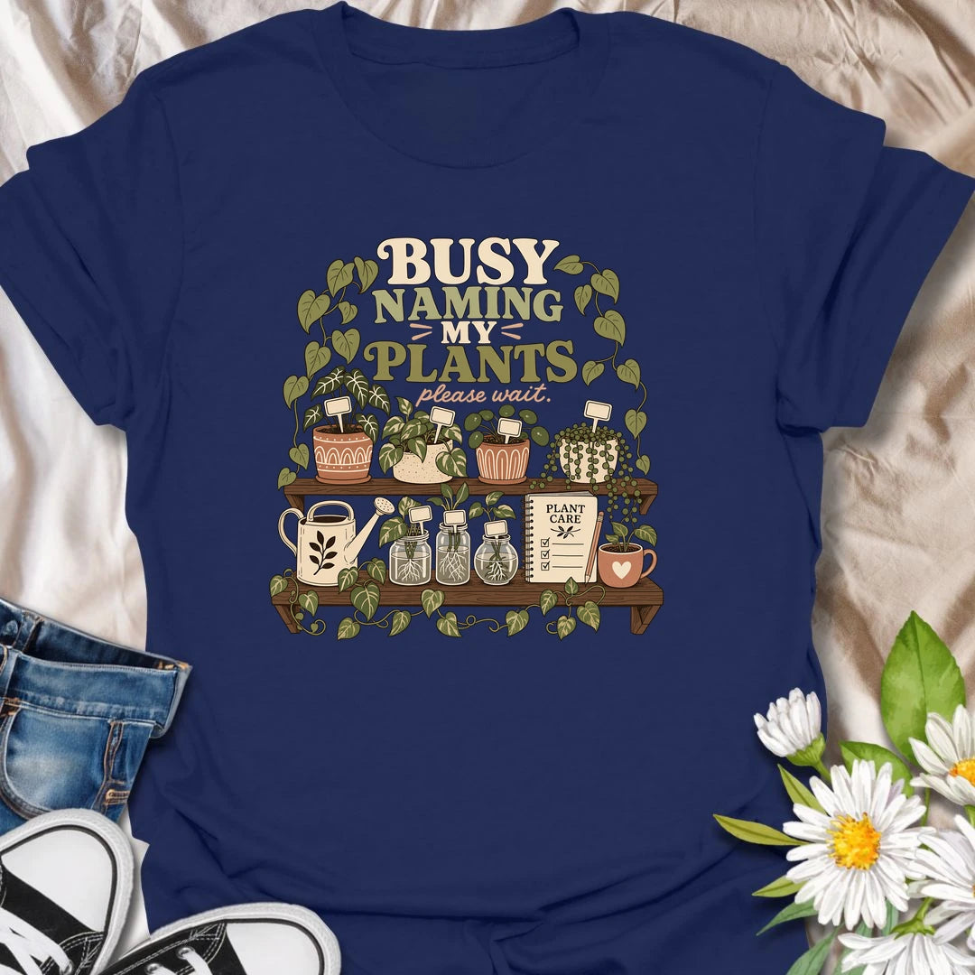 A funny plant lover T-shirt for anyone who treats every houseplant like part of the family. The detailed design features potted plants, propagation jars, gardening tools, and a plant care notebook. A charming gift for plant moms, houseplant collectors, and indoor gardening enthusiasts.