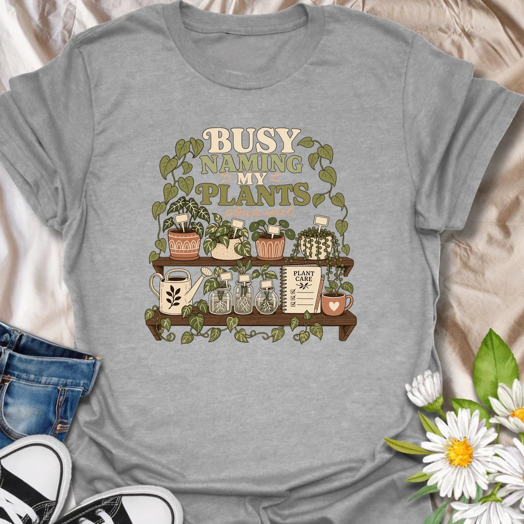 A funny plant lover T-shirt for anyone who treats every houseplant like part of the family. The detailed design features potted plants, propagation jars, gardening tools, and a plant care notebook. A charming gift for plant moms, houseplant collectors, and indoor gardening enthusiasts.