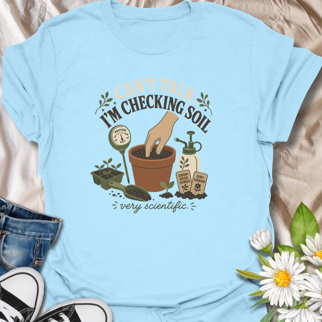A humorous gardening T-shirt for plant lovers who take soil checks very seriously. The design features a terracotta pot, moisture meter, seedlings, mister, and gardening accessories. A fun gift for houseplant owners, gardeners, and anyone regularly caught testing their potting soil.