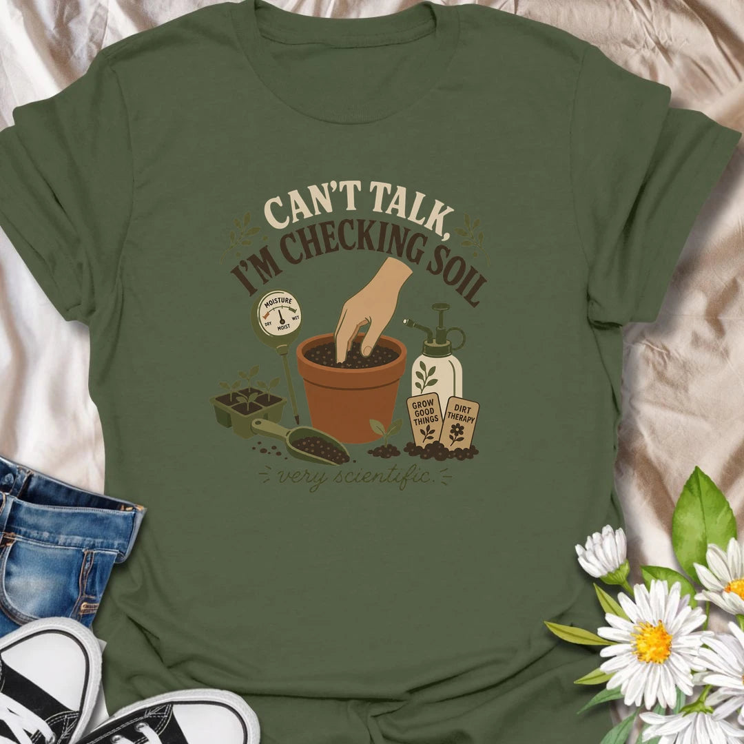 A humorous gardening T-shirt for plant lovers who take soil checks very seriously. The design features a terracotta pot, moisture meter, seedlings, mister, and gardening accessories. A fun gift for houseplant owners, gardeners, and anyone regularly caught testing their potting soil.