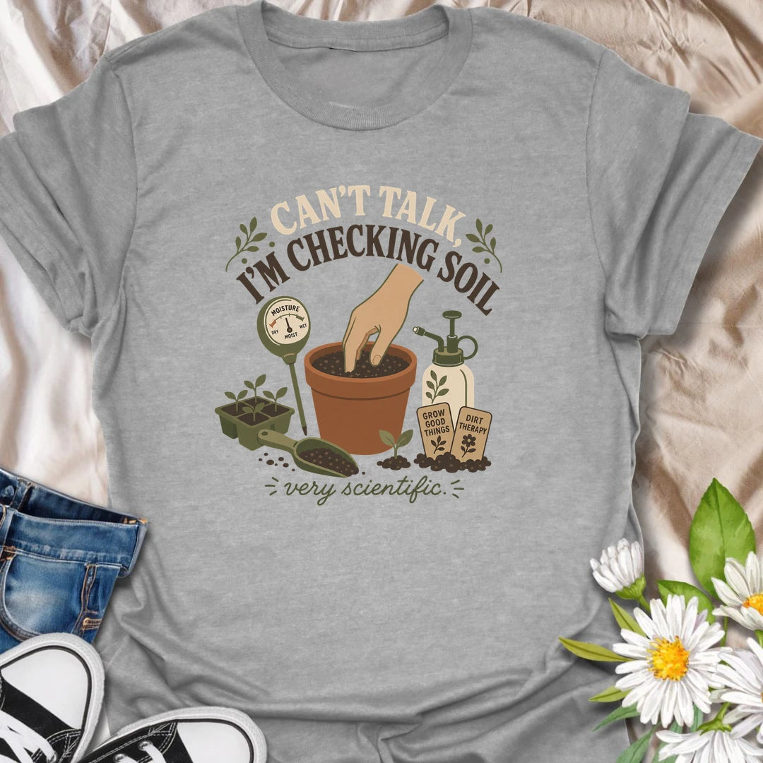 A humorous gardening T-shirt for plant lovers who take soil checks very seriously. The design features a terracotta pot, moisture meter, seedlings, mister, and gardening accessories. A fun gift for houseplant owners, gardeners, and anyone regularly caught testing their potting soil.