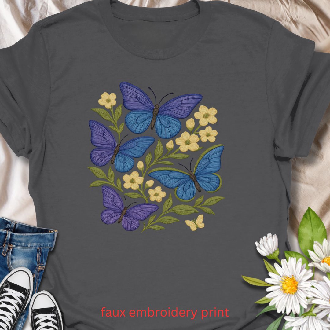Bring whimsical garden vibes to your wardrobe with this faux embroidery butterfly and floral t-shirt. Featuring vibrant blue and purple butterflies among soft yellow flowers, this nature-inspired design mimics stitched embroidery for a cozy, handmade look—without the thread. Perfect for lovers of cottagecore fashion, pollinator gardens, and floral aesthetics.