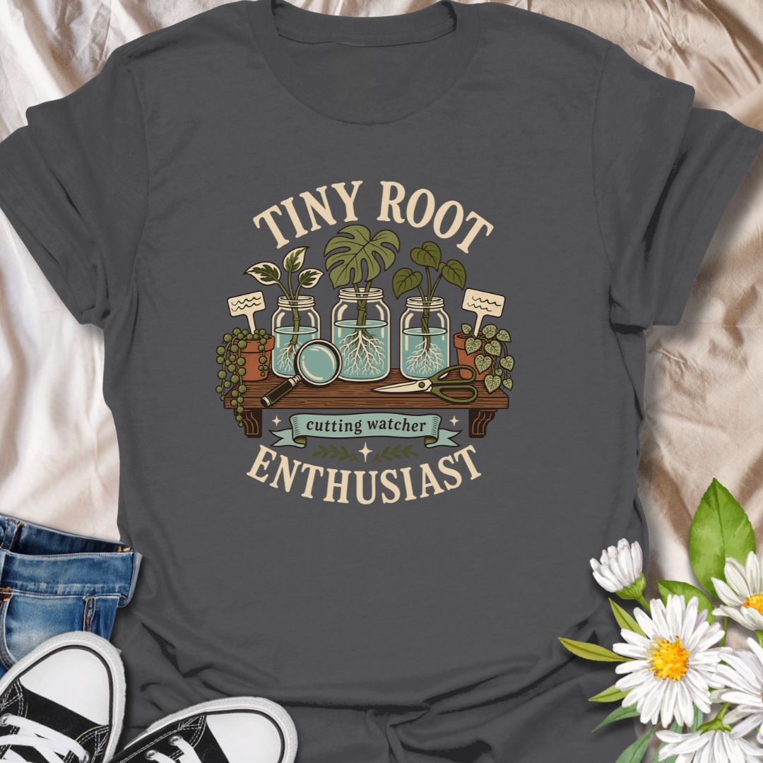 A playful propagation T-shirt for anyone fascinated by the first tiny roots appearing on a cutting. The design features glass jars, water-propagated plants, a magnifying glass, pruning shears, and trailing greenery. A thoughtful gift for houseplant lovers, propagation fans, and patient indoor gardeners.