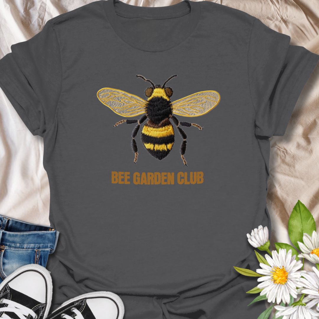 This Bee Garden Club t-shirt is made for gardeners, pollinator lovers, and nature fans who want a simple bee design with a refined botanical feel. Featuring a detailed faux-embroidered bee with golden wings, fuzzy black and yellow stripes, and clean Bee Garden Club lettering, this design has a classic garden-club look that is easy to wear. Perfect for bee lovers, gardeners, wildflower fans, pollinator supporters, nature lovers, and anyone who wants to celebrate the garden’s hardest little workers.