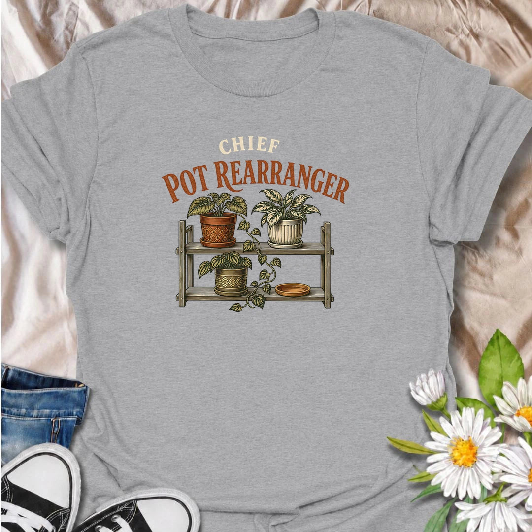 A funny houseplant T-shirt for anyone who can never leave the pots where they are for very long. Featuring a vintage-style plant shelf with patterned pots and trailing greenery, this design is perfect for plant parents who are constantly shifting, styling, and reorganizing their collection. The phrase “Chief Pot Rearranger” captures the familiar habit of moving plants around until everything feels just right. It makes a great gift for houseplant lovers, indoor gardeners, and anyone who treats plant shelves 