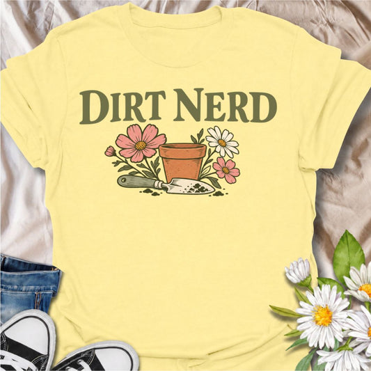 A playful gardening T-shirt for anyone who genuinely gets excited about soil, pots, planting, and everything that goes with growing things. The simple “Dirt Nerd” phrase pairs with flowers, a terracotta pot, and hand trowel for a clean garden-lover design with plenty of personality. It is perfect for backyard gardeners, flower growers, cottage gardeners, and anyone who is happiest with their hands in the soil. The soft vintage-style artwork keeps the design cheerful and easy to wear. A great gift for garden