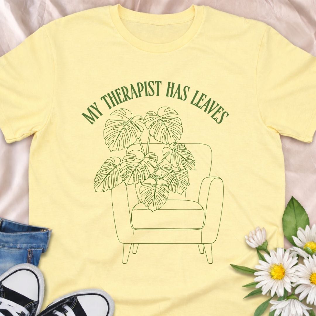 For plant people who spill their heart out to their houseplants, this “My Therapist Has Leaves” t-shirt says it all. Features a cozy armchair and lush monstera, making it the perfect aesthetic plant lover tee for self-care days.