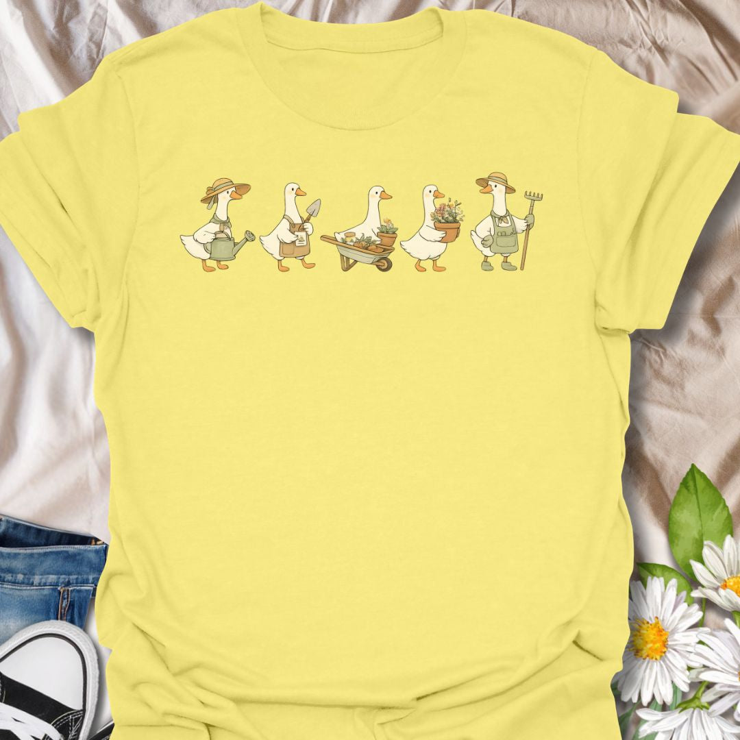 This Gardening Geese t-shirt is made for gardeners, plant lovers, and anyone who enjoys cute nature-inspired artwork with a little humor. Featuring a row of charming geese carrying watering cans, garden tools, flower pots, a wheelbarrow, and fresh plants, this design has a playful cottagecore garden feel that is easy to wear. Perfect for gardeners, duck lovers, plant moms, flower fans, backyard growers, and anyone who thinks garden chores are better with a gaggle of helpful Geese.