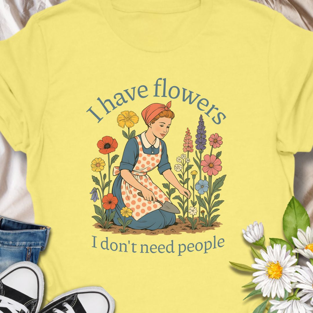 Express your introverted, plant-loving side with this charming floral t-shirt. Perfect for gardeners, plant moms, or anyone who finds peace in flowers over people — it's a blooming statement of self-care.  This tee pairs vintage garden charm with a wry sense of independence. A retro-style gardener tends bright, cottage blooms while the caption reads “I have flowers / I don’t need people.” 